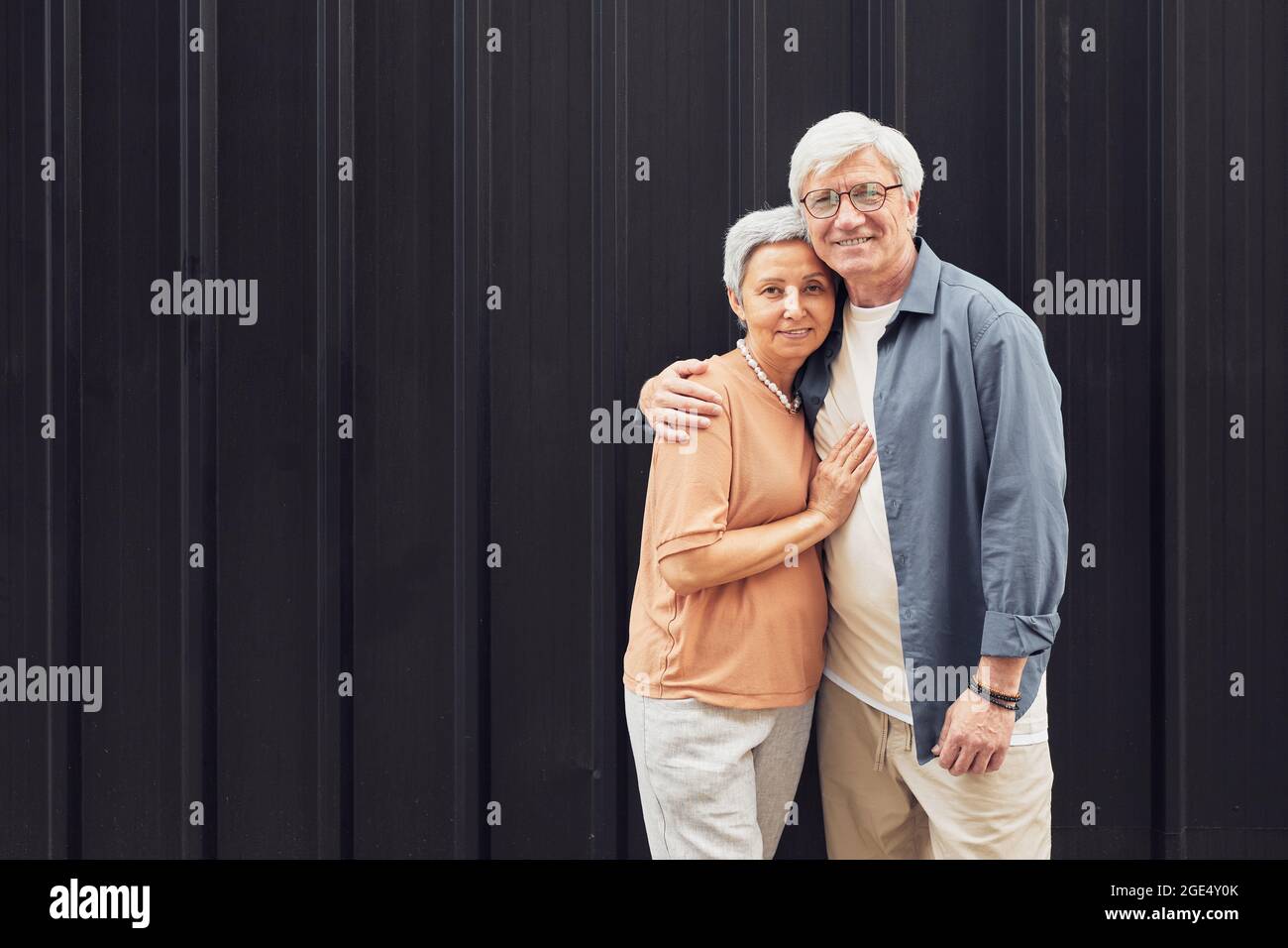 Portrait minimal d'un couple moderne et mûr avec un appareil photo at6 tout en se tenant sur un arrière-plan noir, dans un espace de copie Banque D'Images