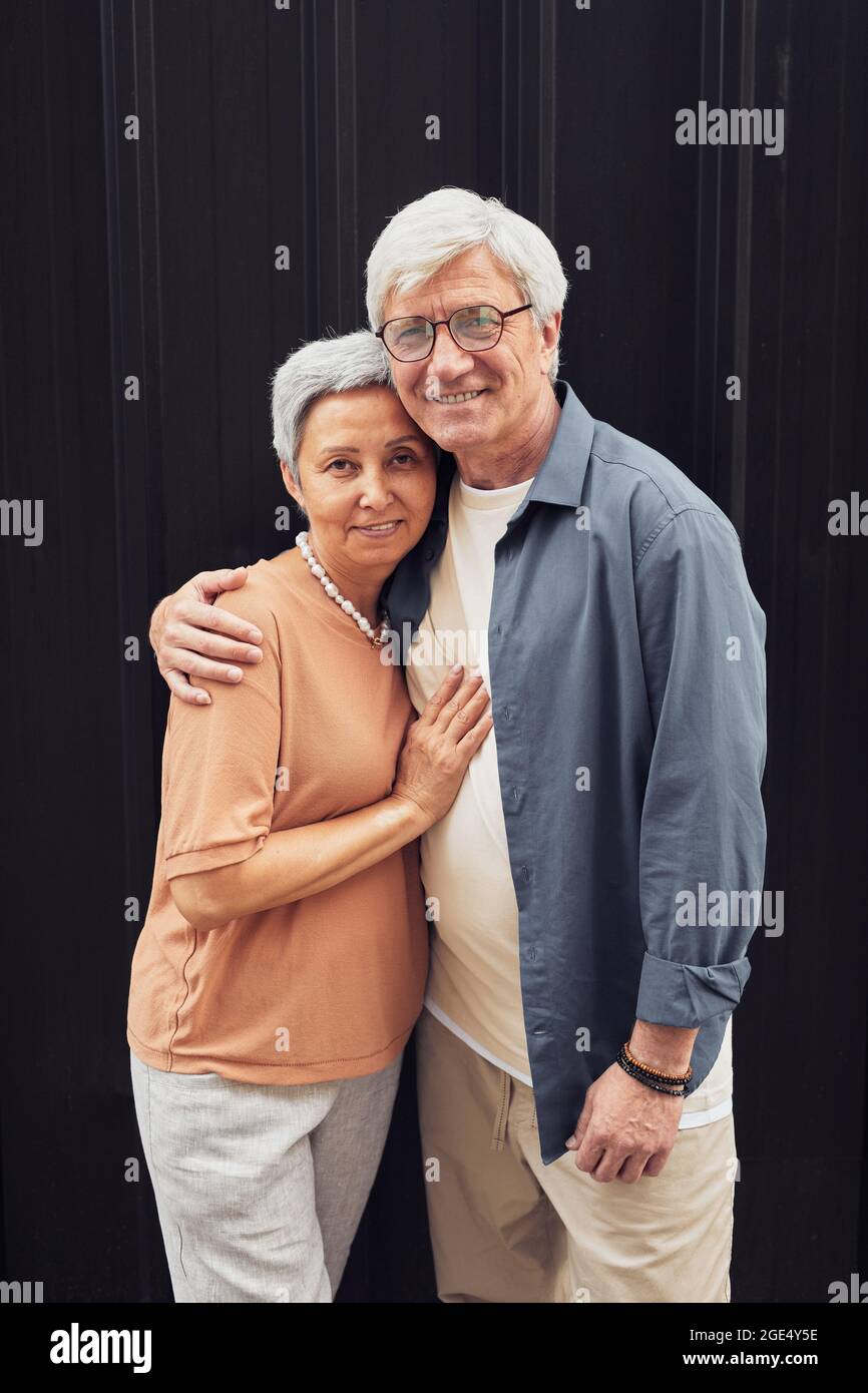 Portrait vertical d'un couple moderne et mûr avec un appareil photo at6 et debout sur un arrière-plan noir Banque D'Images