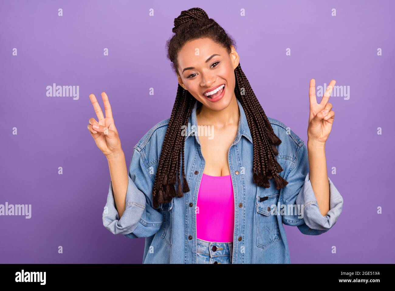 Portrait d'une jolie fille gaie funky montrant le double V-signe ayant l'amusement isolé sur fond violet vif rouge couleur rouge Banque D'Images