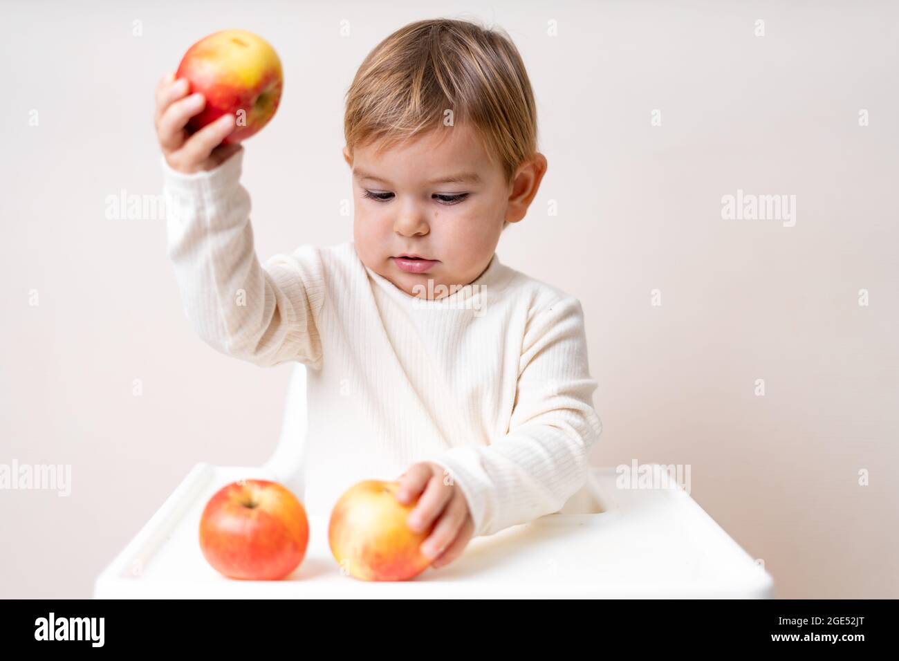 Bébé avec des pommes sur la chaise haute. Une alimentation saine. Récolte d'été et d'automne. Prise de vue en studio Banque D'Images