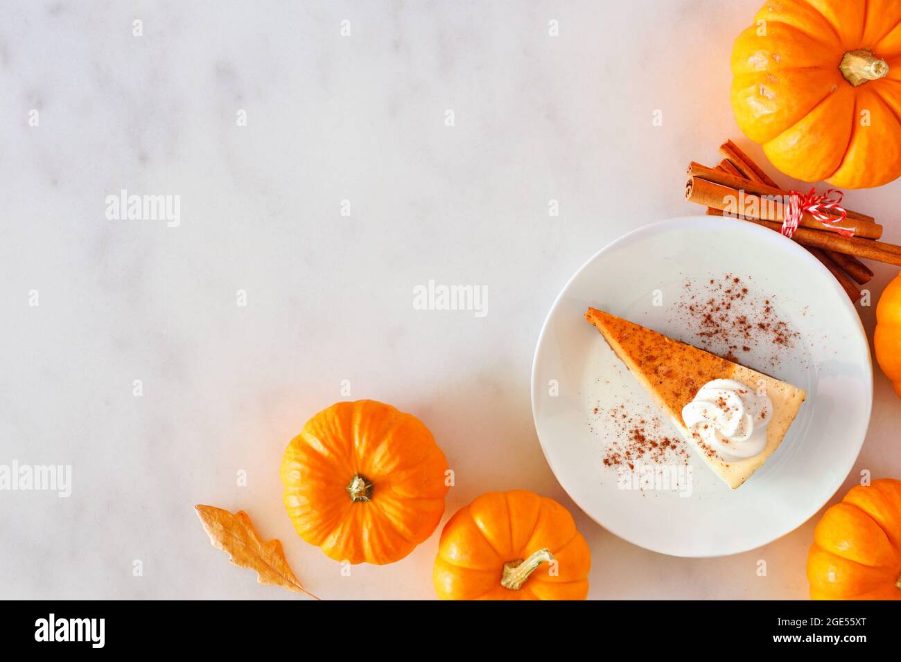 Tranche de gâteau au fromage à la citrouille et crème fouettée. Vue de dessus, bordure d'angle sur fond de marbre blanc. Banque D'Images