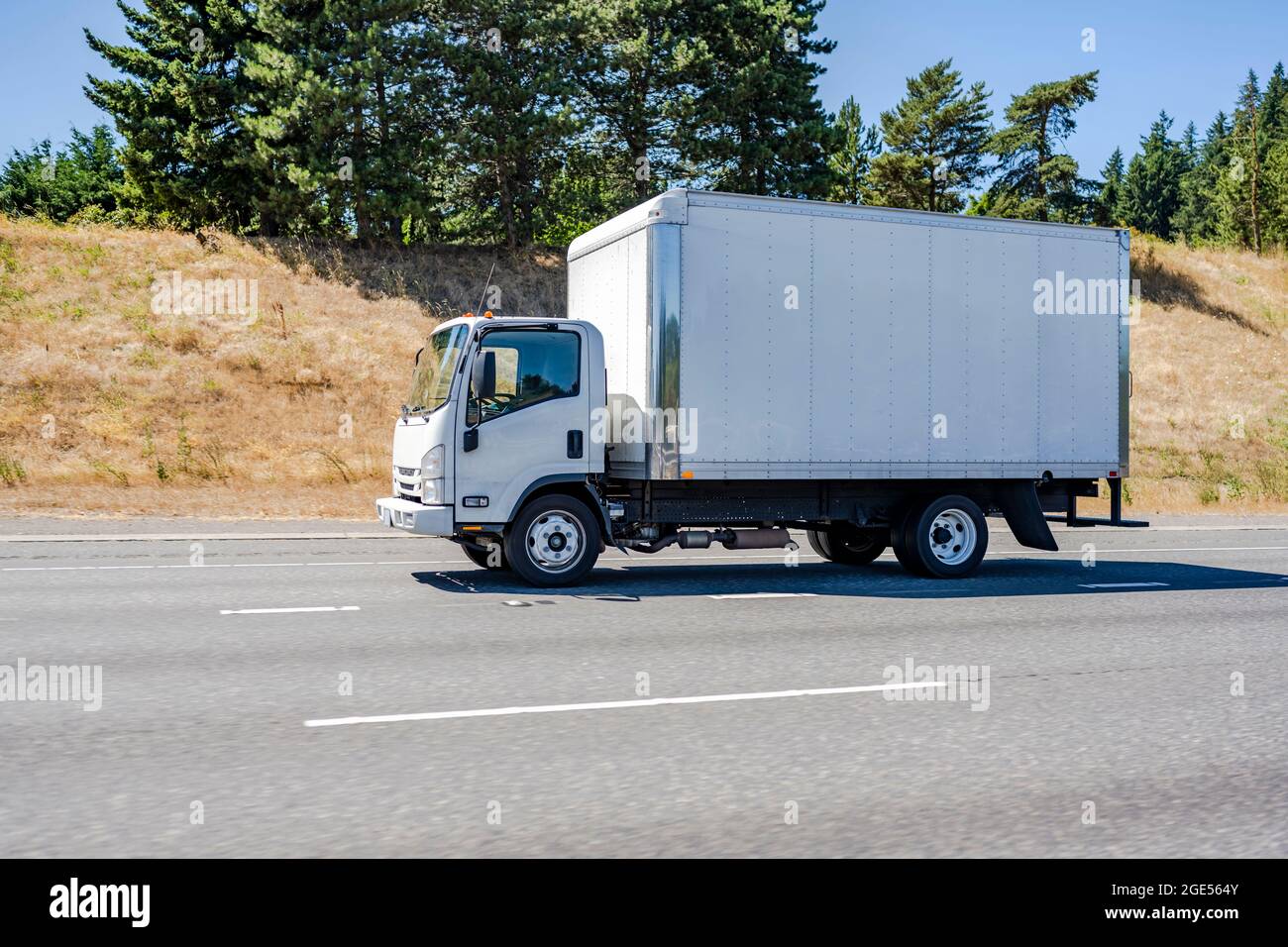 Petit tracteur classique à cabine blanche sur semi-remorque avec remorque à caisse pour les livraisons locales de fret commercial sur la route large Banque D'Images