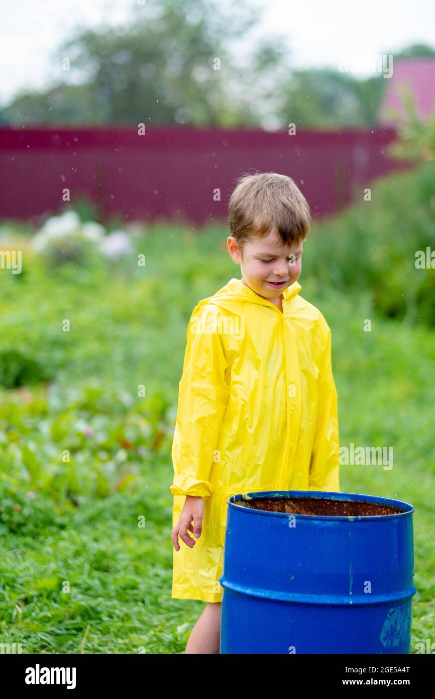 Un garçon sous un imperméable jaune marche dehors sous la pluie. Enfant  magnifique et souriant dans la rue. Des vêtements brillants. Marchez sous  la pluie Photo Stock - Alamy