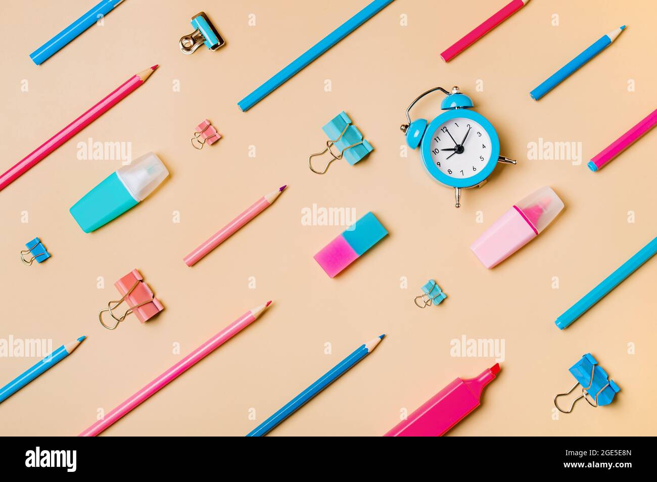 Bureau étudiant créatif fournitures scolaires modernes sur fond beige pastel neutre. Plan d'étapage avec vue de dessus. Concept de retour à l'école. Motif diagonal avec crayons, stylos, marqueurs, radio-réveil, trombones Banque D'Images
