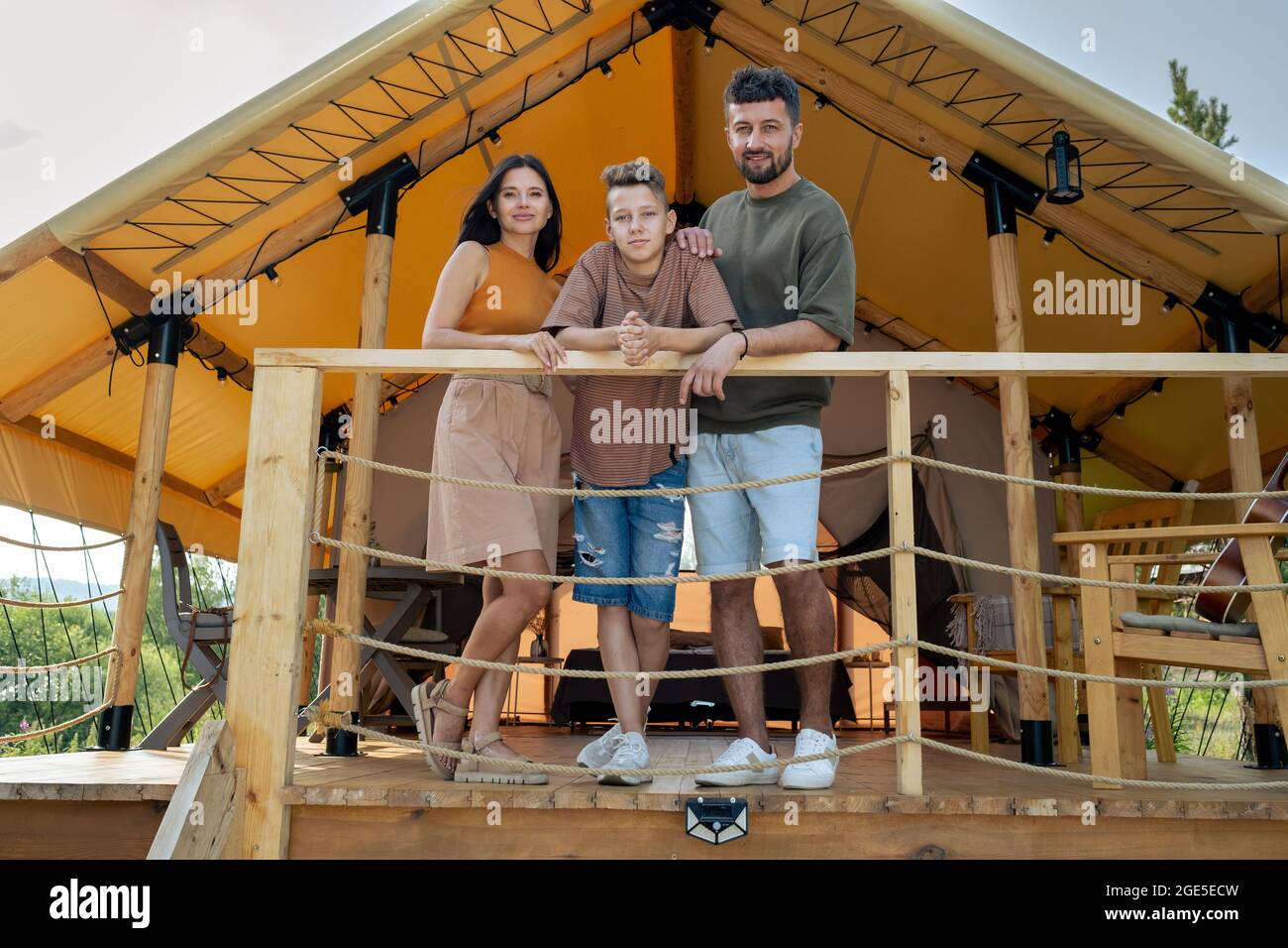 Un jeune mari, une femme et leur fils adolescent profitent de vacances d'été dans une maison de glamping Banque D'Images