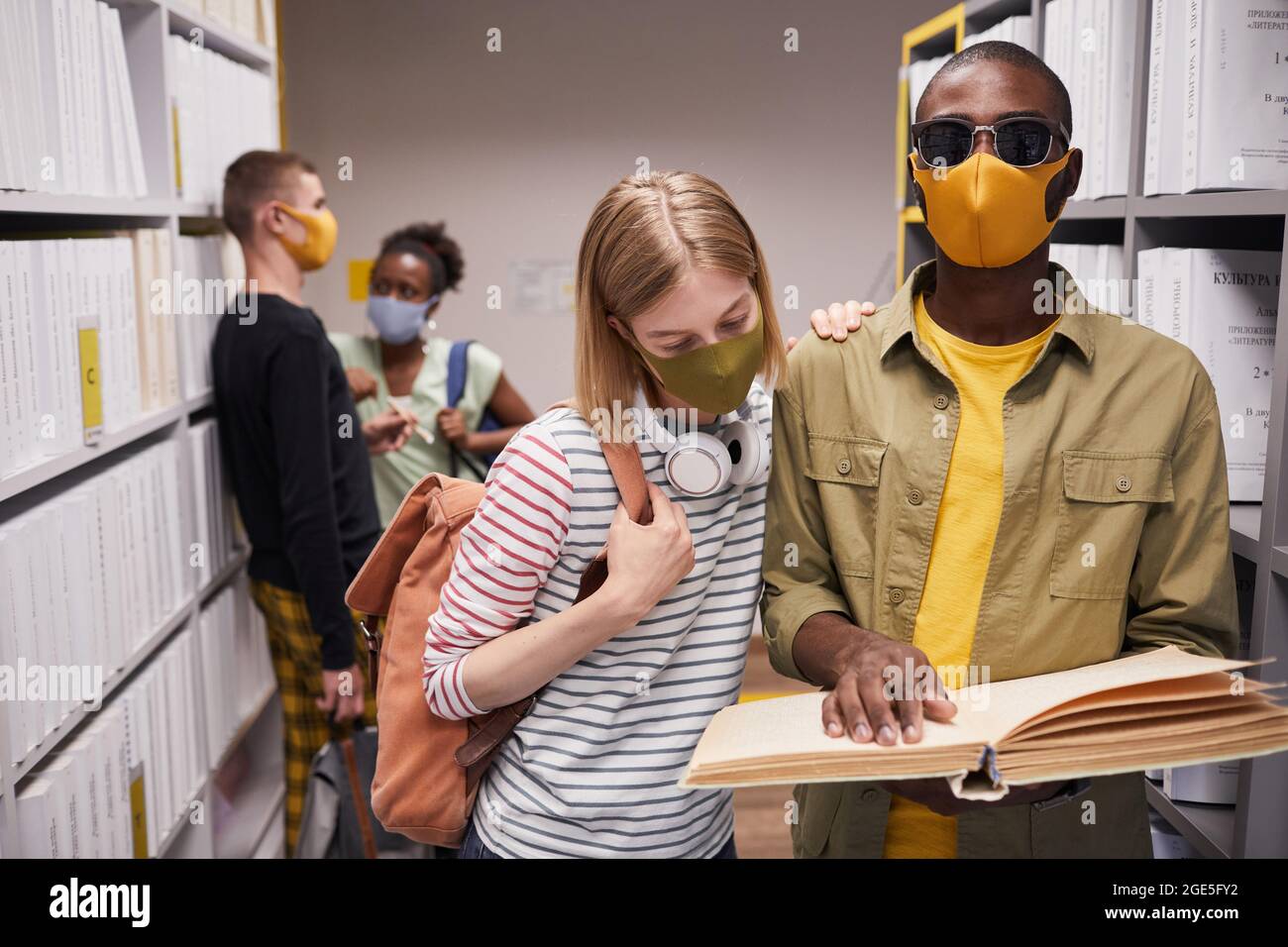 Portrait à la taille d'un groupe diversifié d'élèves en bibliothèque avec un homme aveugle en premier plan Banque D'Images