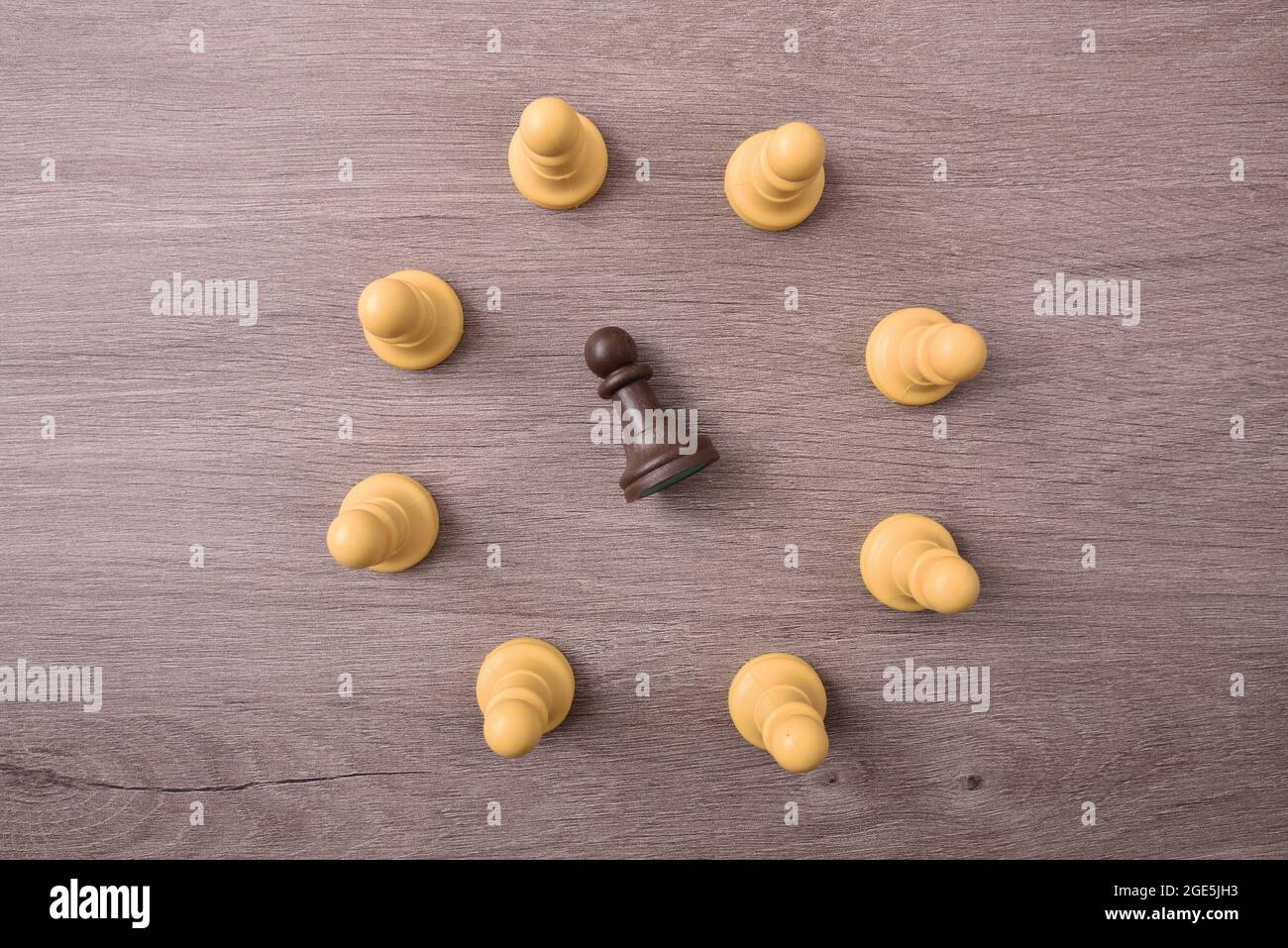 Social brimades concept avec des pièces d'échecs blanches faisant un cercle de virage une pièce noire au milieu couché sur le sol Banque D'Images