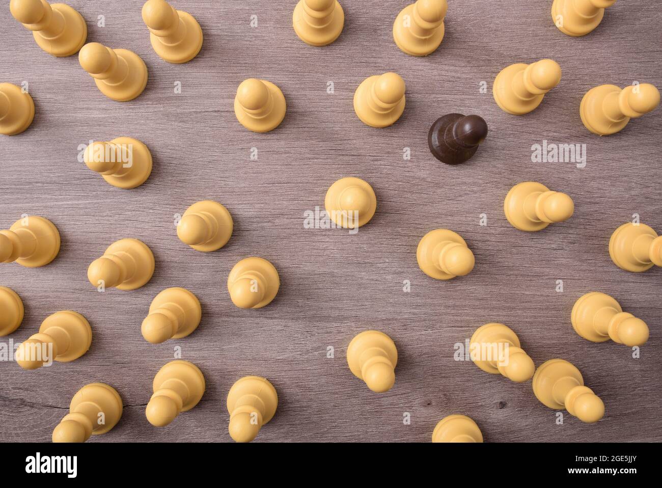 Concept de différence sociale avec pièce d'échecs noire entourée de pièces blanches sur table en bois. Vue de dessus. Banque D'Images