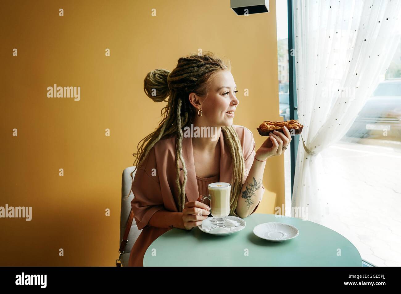Femme caucasienne avec des dreadlocks assis dans un café et tenir eclair. Portrait décontracté de la jeune femme. Banque D'Images