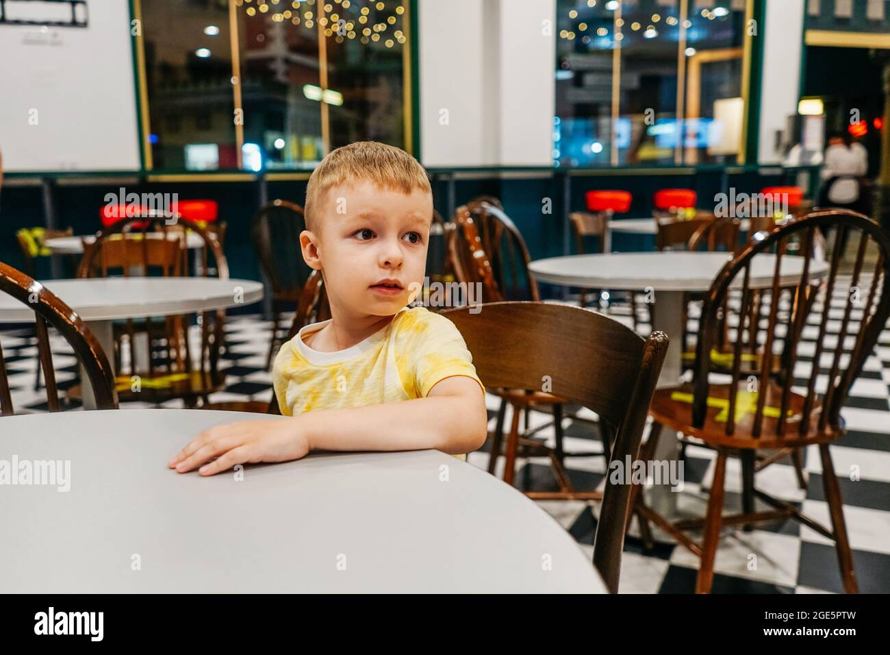 Enfant assis dans un café américain et attendant une pizza. Banque D'Images