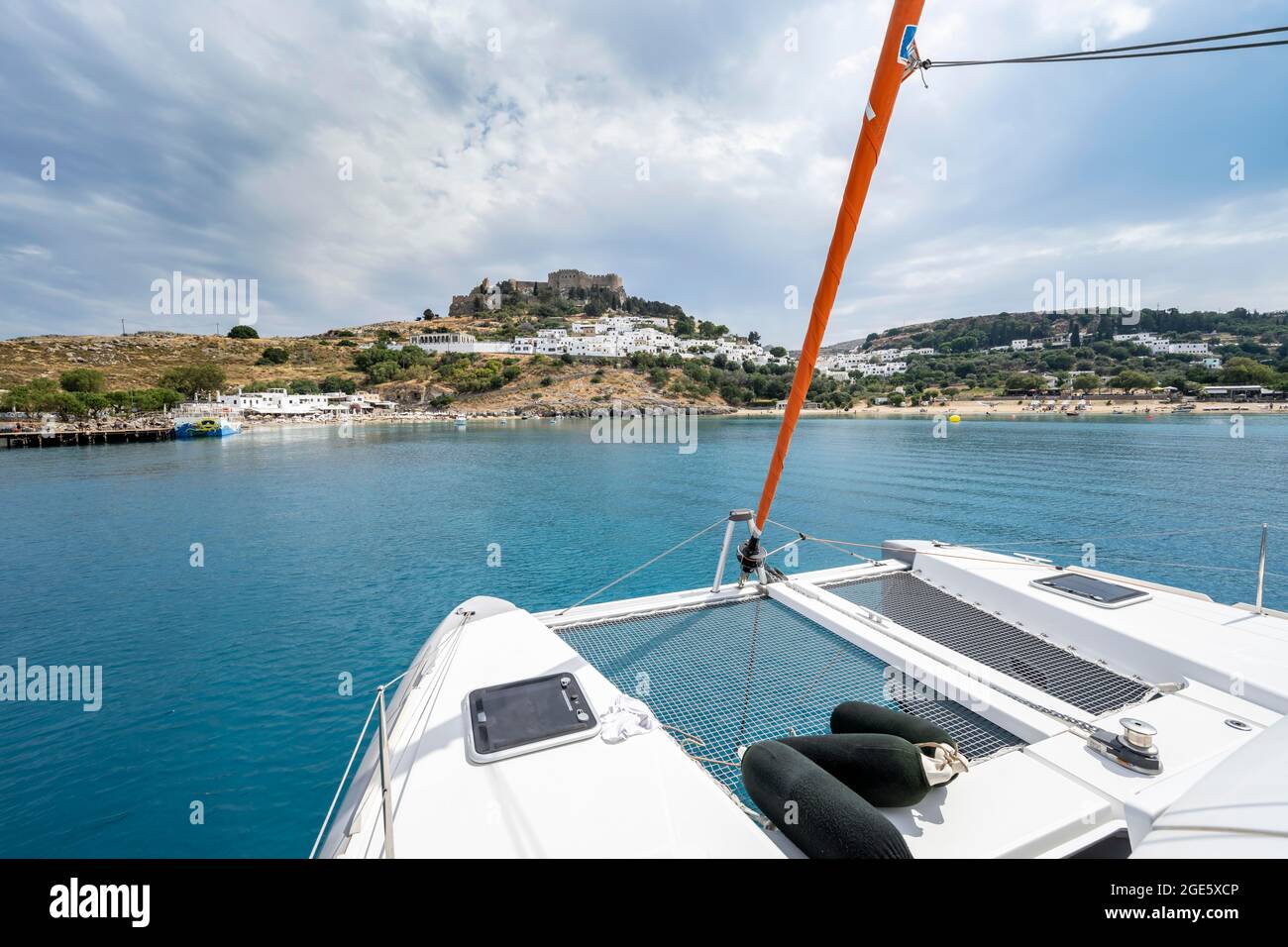 Pont d'un catamaran à voile avec filet et ailes, Lindos et Acropole de Lindos à l'arrière, baie de Lindos, Rhodes, Grèce Banque D'Images Pont d'un catamaran à voile avec filet et ailes, Lindos et Acropole de Lindos à l'arrière, baie de Lindos, Rhodes, Grèce Banque D'Images