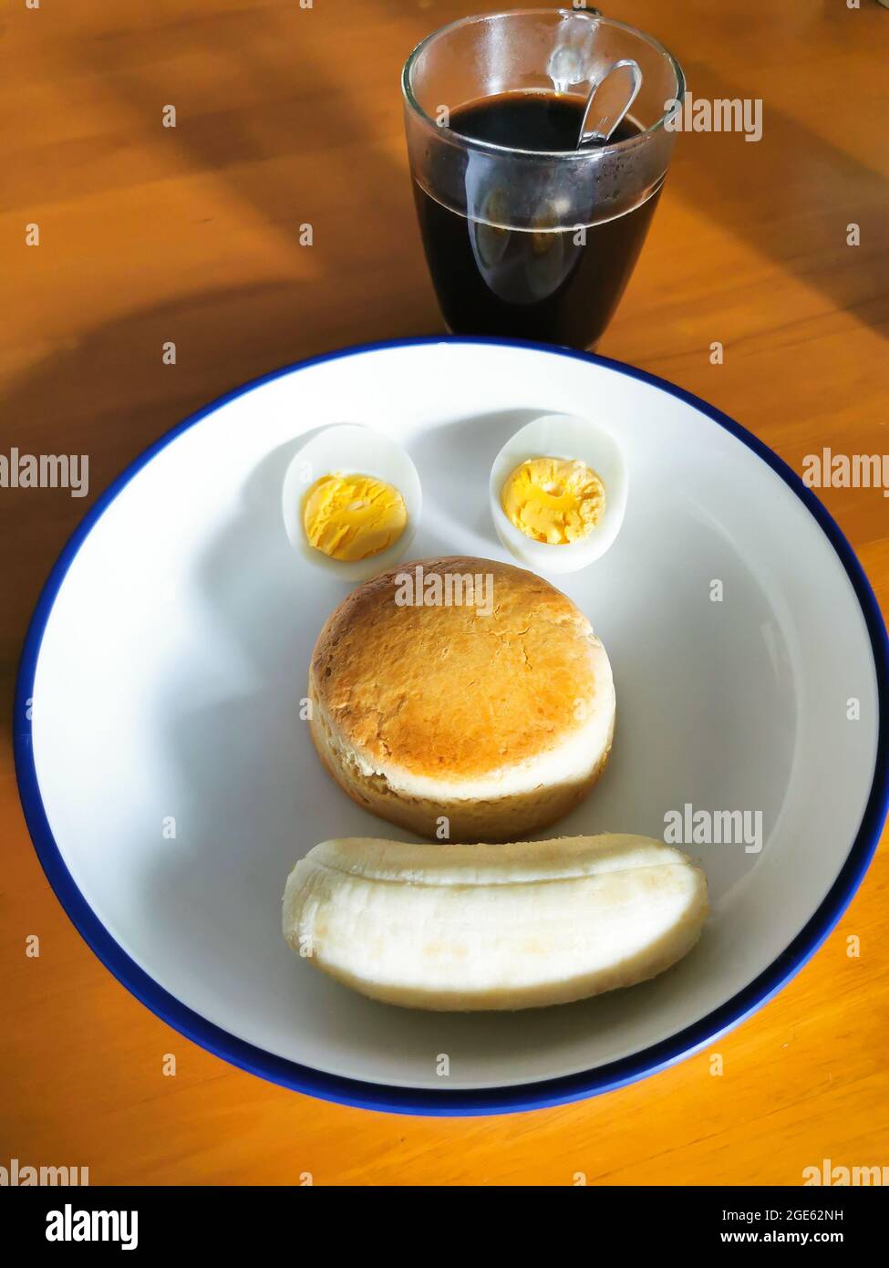 Plats faits maison servis sur une assiette ronde blanche sur une table en bois. Une tasse de café est placée sur le côté de la plaque alimentaire. Dans la plaque alimentaire ont coupé des tranches d'œufs durs, de la tarte Banque D'Images