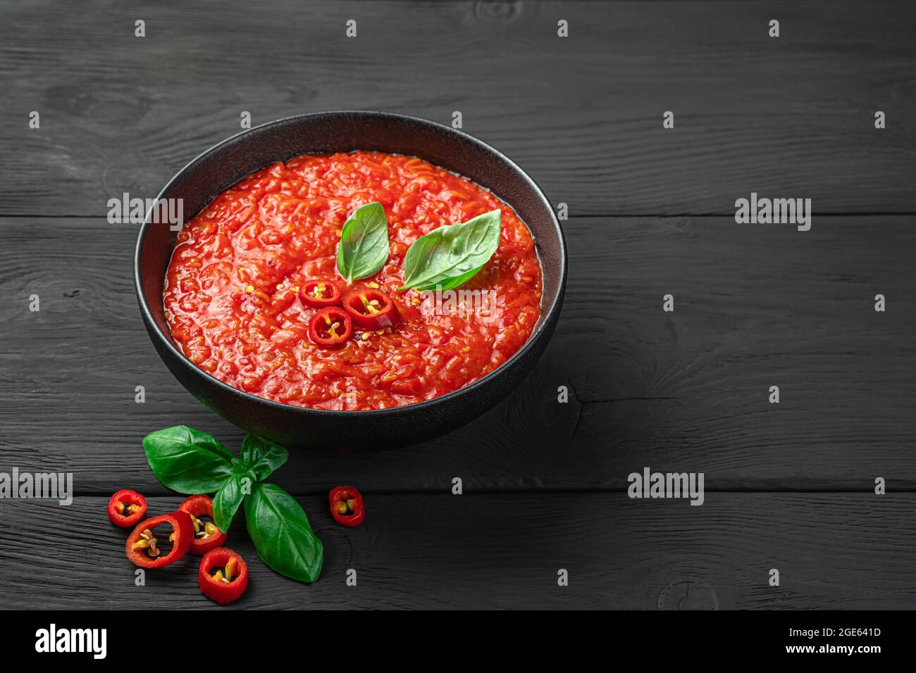 Sauce tomate épicée au basilic dans un bol sur fond noir. Banque D'Images