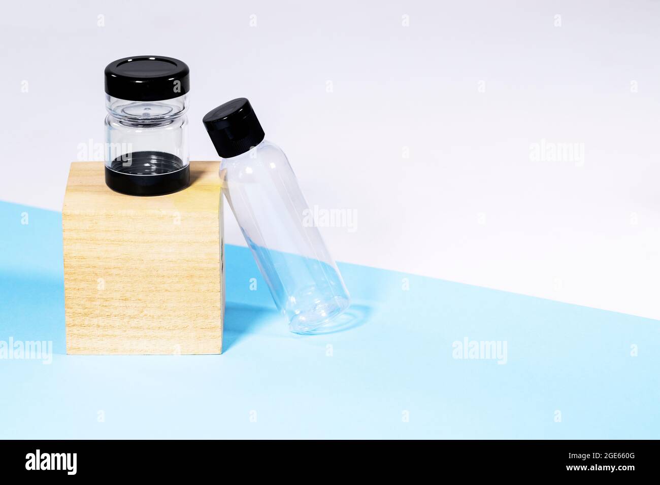 Bouteilles de voyage transparentes en plastique pour cosmétiques sur podium en bois : savon, gel, lotion, crème, shampooing, Maquillage et liquides sur fond bleu. Moderne Banque D'Images