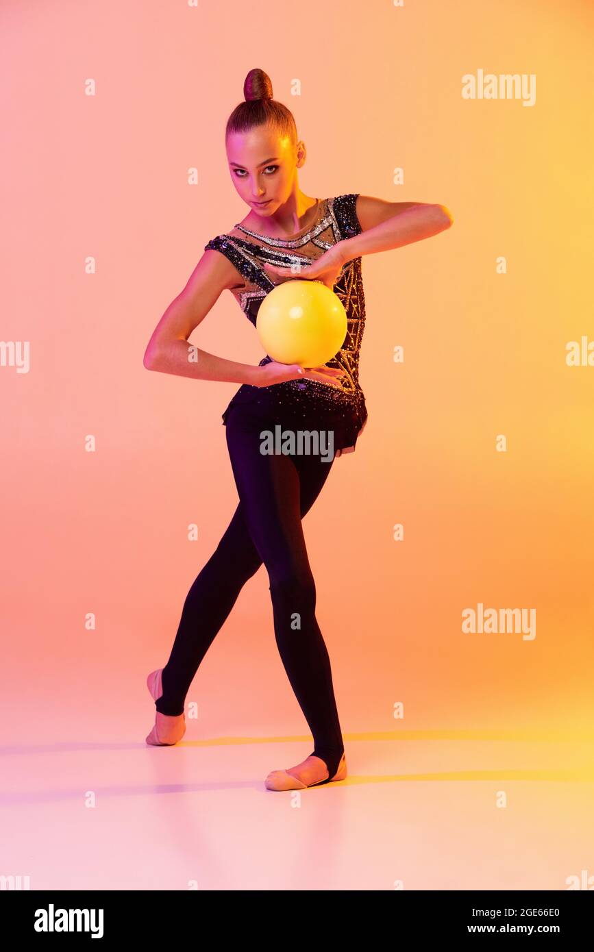Une jeune fille, artiste de gymnastique rythmique en tenue de scène,  costume de sport isolé sur fond rose jaune studio au néon. Concept de sport  Photo Stock - Alamy