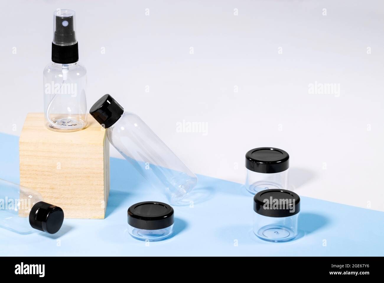 Bouteilles de voyage transparentes en plastique pour cosmétiques sur podium en bois : savon, gel, lotion, crème, shampooing, maquillage et liquides. Concept de voyage moderne. Copier Banque D'Images