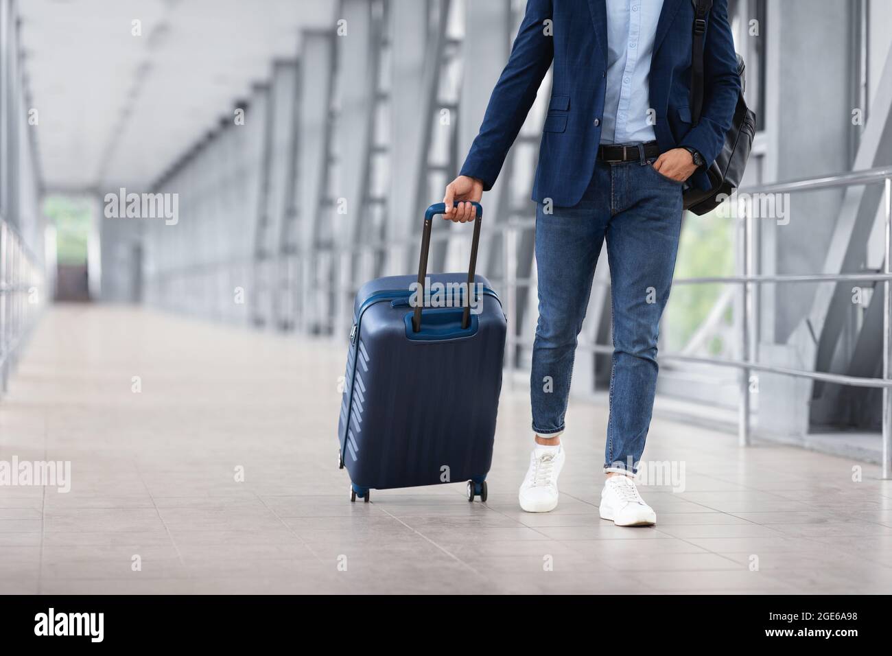 Homme méconnaissable en vêtements décontractés marchant avec des bagages au terminal de l'aéroport, voyageur masculin se rendant à la porte d'embarquement avec Suitcase, prêt pour les affaires Banque D'Images