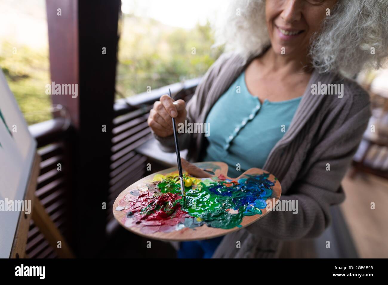 Bonne femme de race blanche debout sur un balcon ensoleillé et de la peinture Banque D'Images