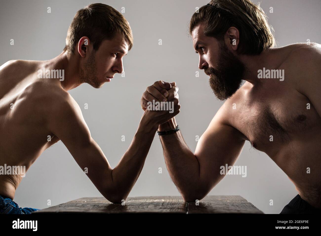Homme barbu fortement musclé bras luttant un homme faible et puny. Bras luttant main mince, gros bras fort en studio. Deux mains d'homme ont classé le bras luttant Banque D'Images