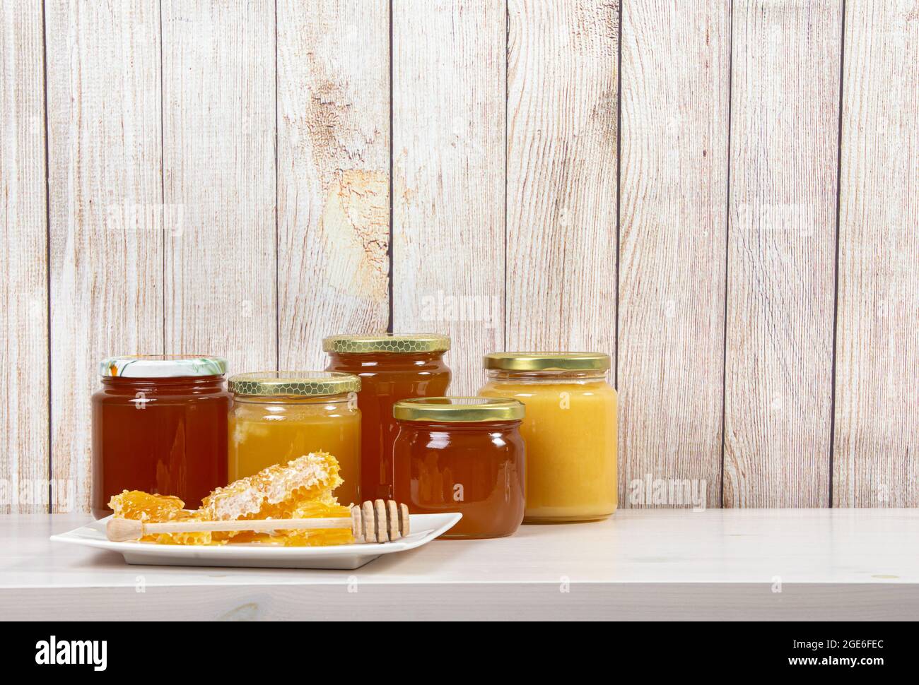 Divers pots de miel avec différentes couleurs miel, beaucoup d'espace de copie sur fond de bois clair. Concept de fond de bordure de miel. Banque D'Images
