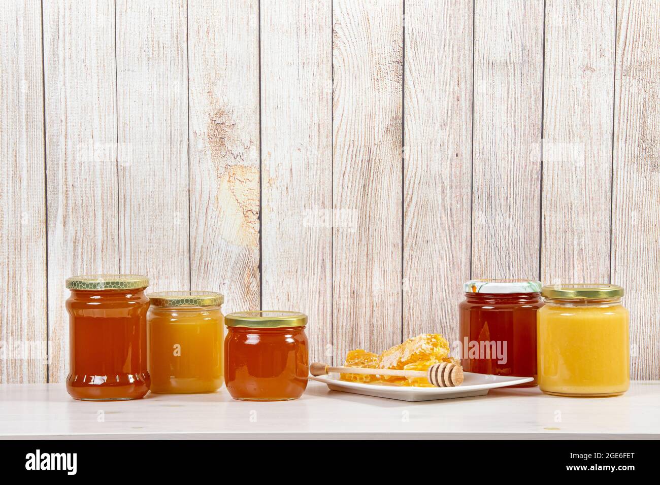 Divers pots de miel avec différentes couleurs miel, beaucoup d'espace de copie sur fond de bois clair. Concept de fond de bordure de miel. Banque D'Images