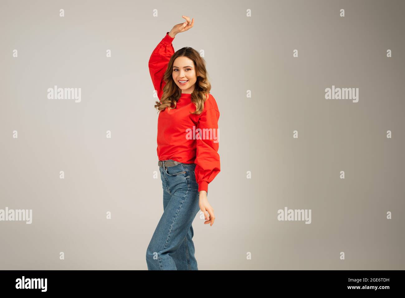 bonne femme en sweat-shirt avec main levée regardant la caméra isolée sur gris Banque D'Images