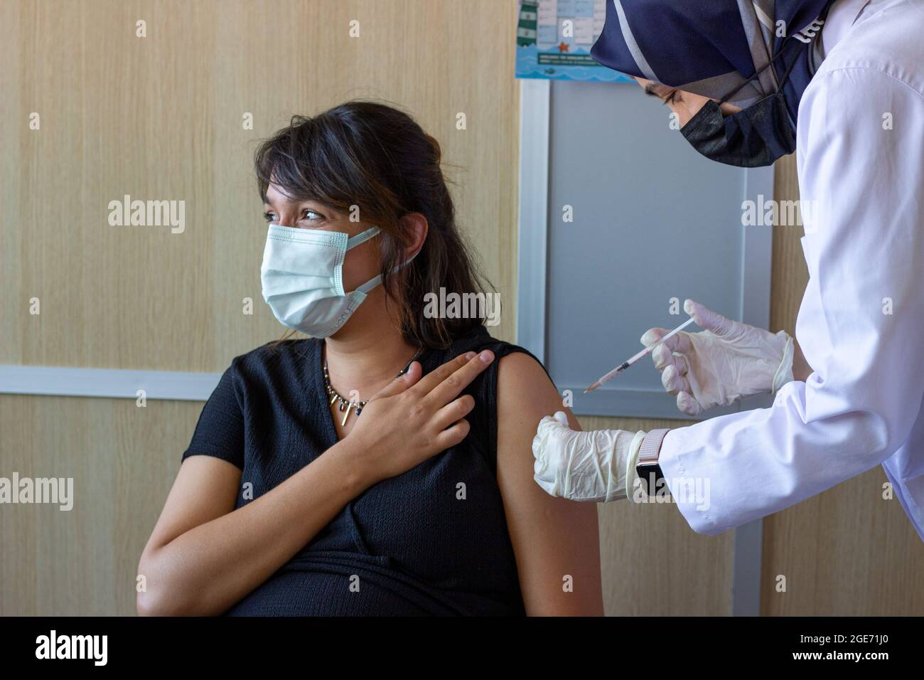 La femme enceinte se fait vacciner.Vaccin contre l'hépatite, la grippe, la diphtérie ou le covid.La femme avec enceinte évidente.Femme musulmane Docteur ou infirmière main. Banque D'Images