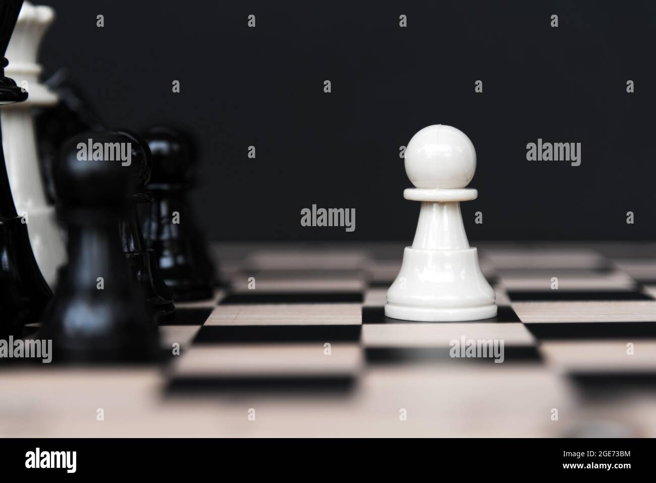 Jeu d'échecs blanc en face de la rangée d'échecs noirs sur fond noir Banque D'Images