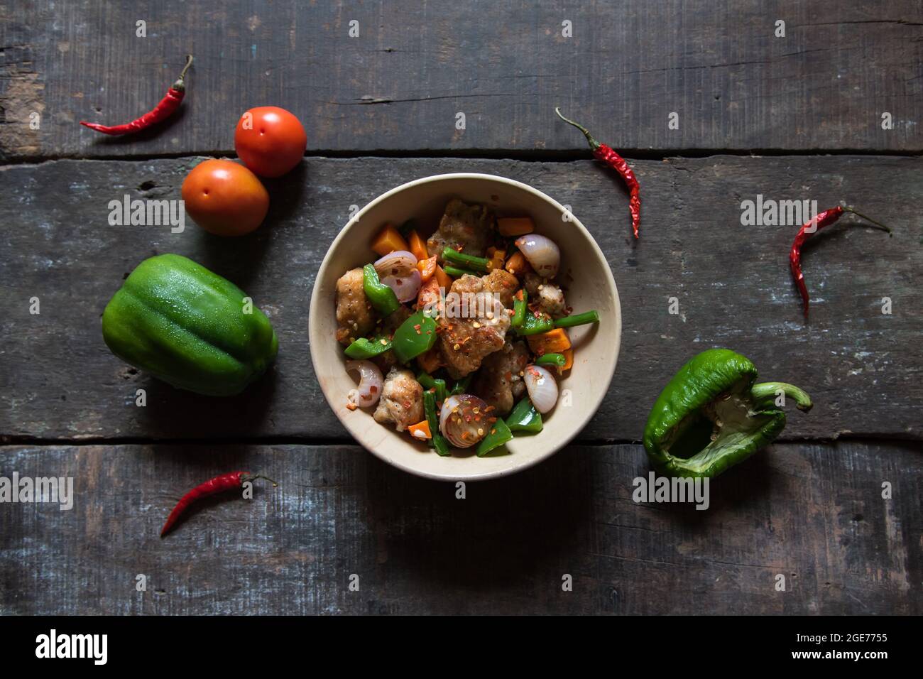 Vue de dessus des morceaux de poulet saute avec des légumes et garni d'origan et de flocons de piment. Banque D'Images