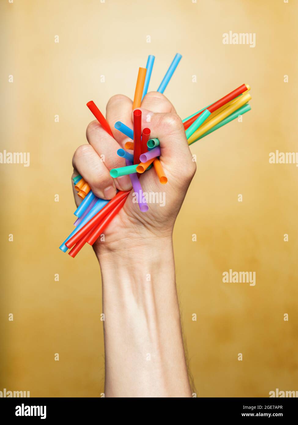 La main de l'homme écrasant des pailles en plastique colorées Banque D'Images