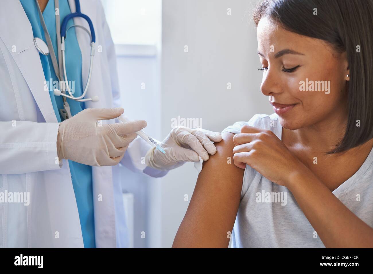 Jeune femme afro-américaine heureuse recevant une injection du vaccin coronavirus en clinique Banque D'Images