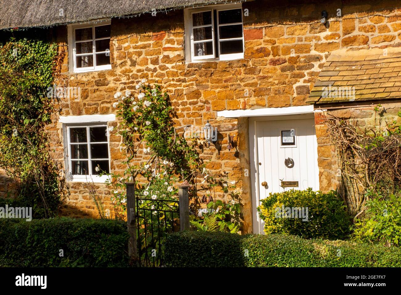 Royaume-Uni, Angleterre, Oxfordshire, Shenington, Kenhill Road, Porte peinte en blanc de caractère Cotswolds en pierre chaume cottage Banque D'Images