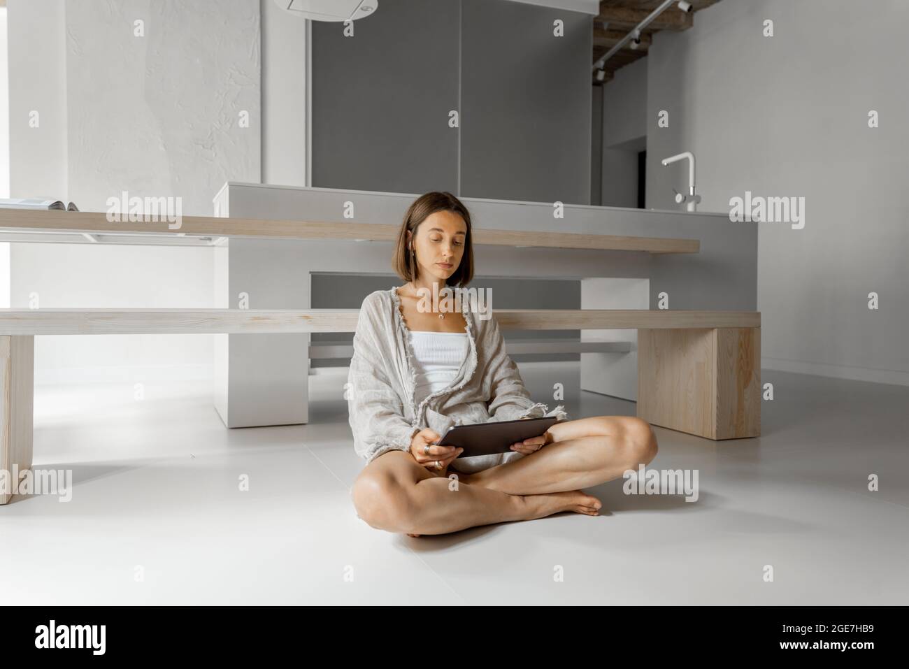 Femme travaille sur une tablette numérique tout en étant détendue dans un appartement moderne Banque D'Images