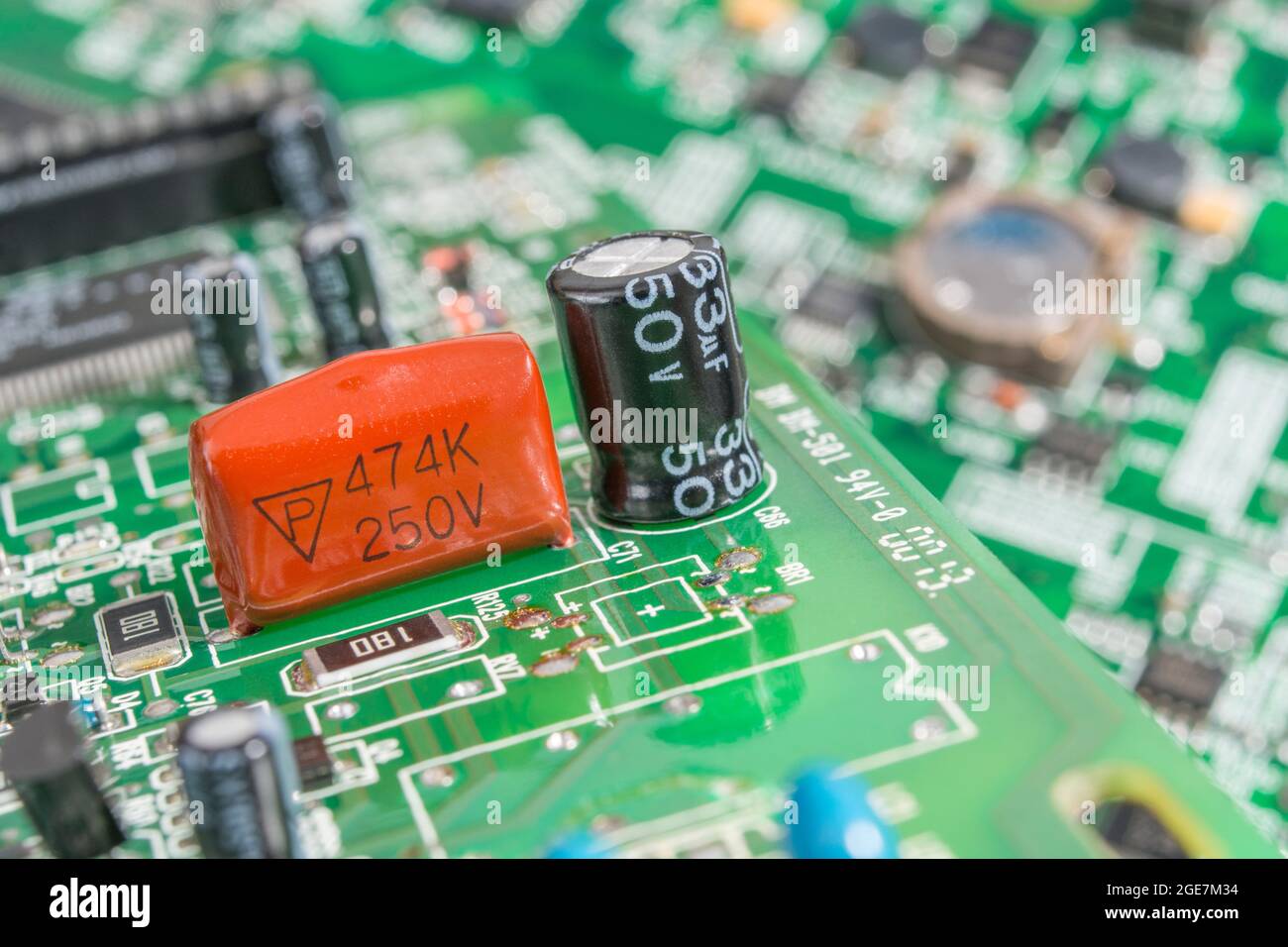 Gros plan du condensateur à film polyester trempé de couleur orange sur la carte de circuit imprimé verte. Pour condensateur au plomb, petits composants électroniques. Fabricant non identifié Banque D'Images