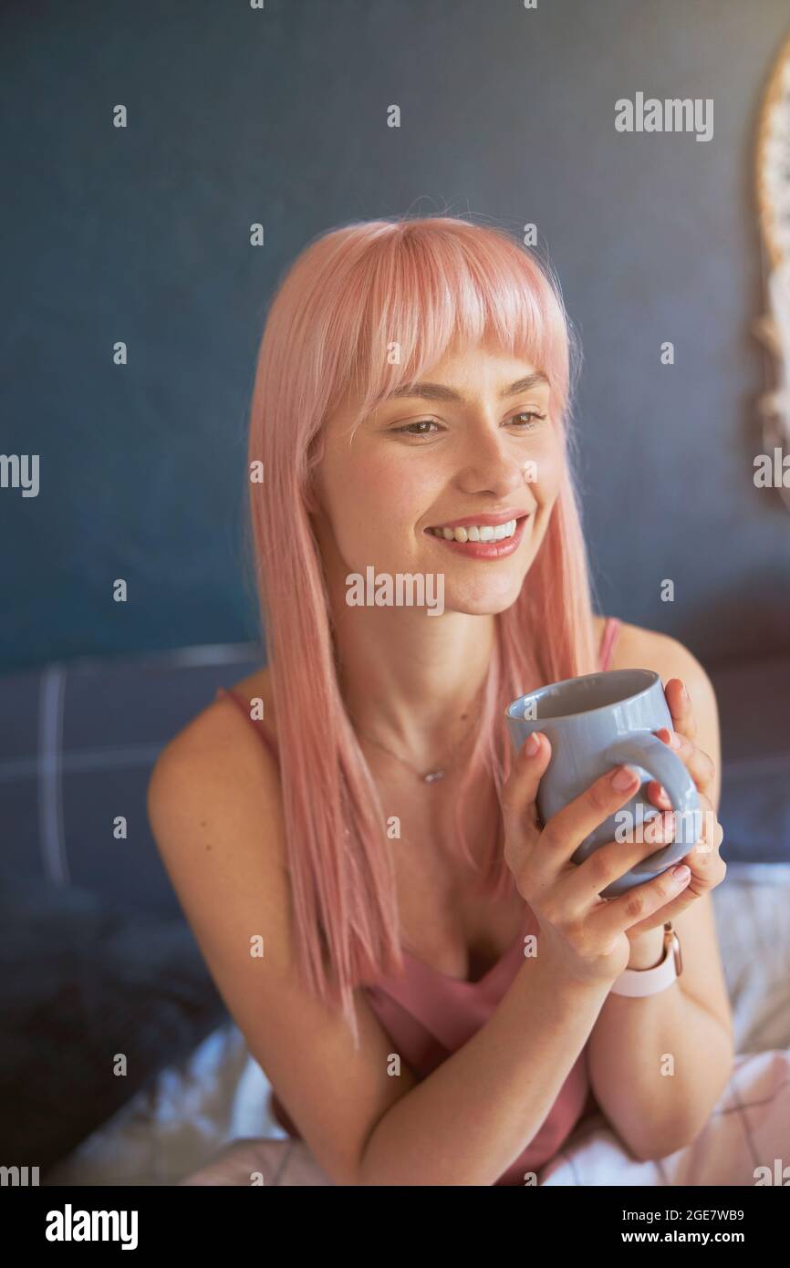 Le joli mannequin féminin peut contenir une tasse de boisson délicieuse sur le lit Banque D'Images
