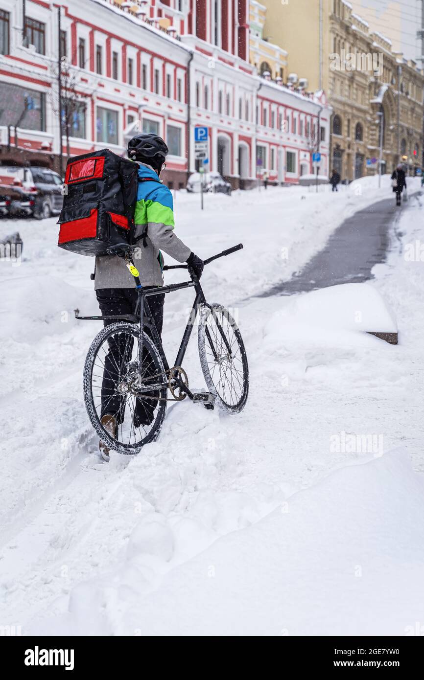 Non reconnaissable liveur avec vélo travaillant en hiver, rue de la ville Banque D'Images