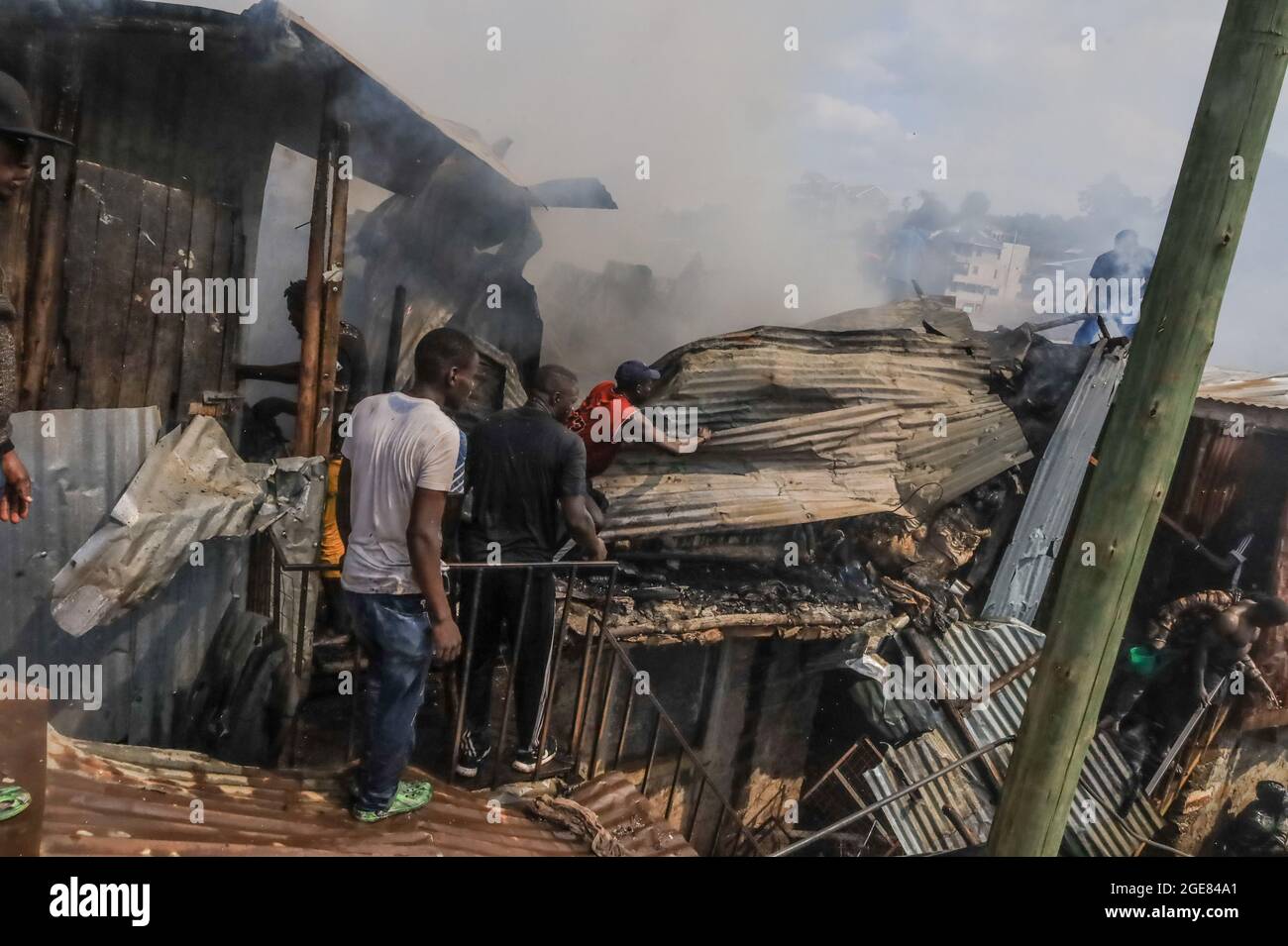 Nairobi, Kenya. 17 août 2021. Les résidents ont vu des toits qui essayaient de déclencher un incendie à Bombolulu, Kibera.les résidents se sont joints aux mains pour aider à faire un incendie qui s'est produit aujourd'hui après-midi à partir de fils électriques emmêlés alimentant différentes maisons en électricité. Le feu a rasé douze maisons et propriétés laissant la plupart des résidents bloqués. Crédit : SOPA Images Limited/Alamy Live News Banque D'Images