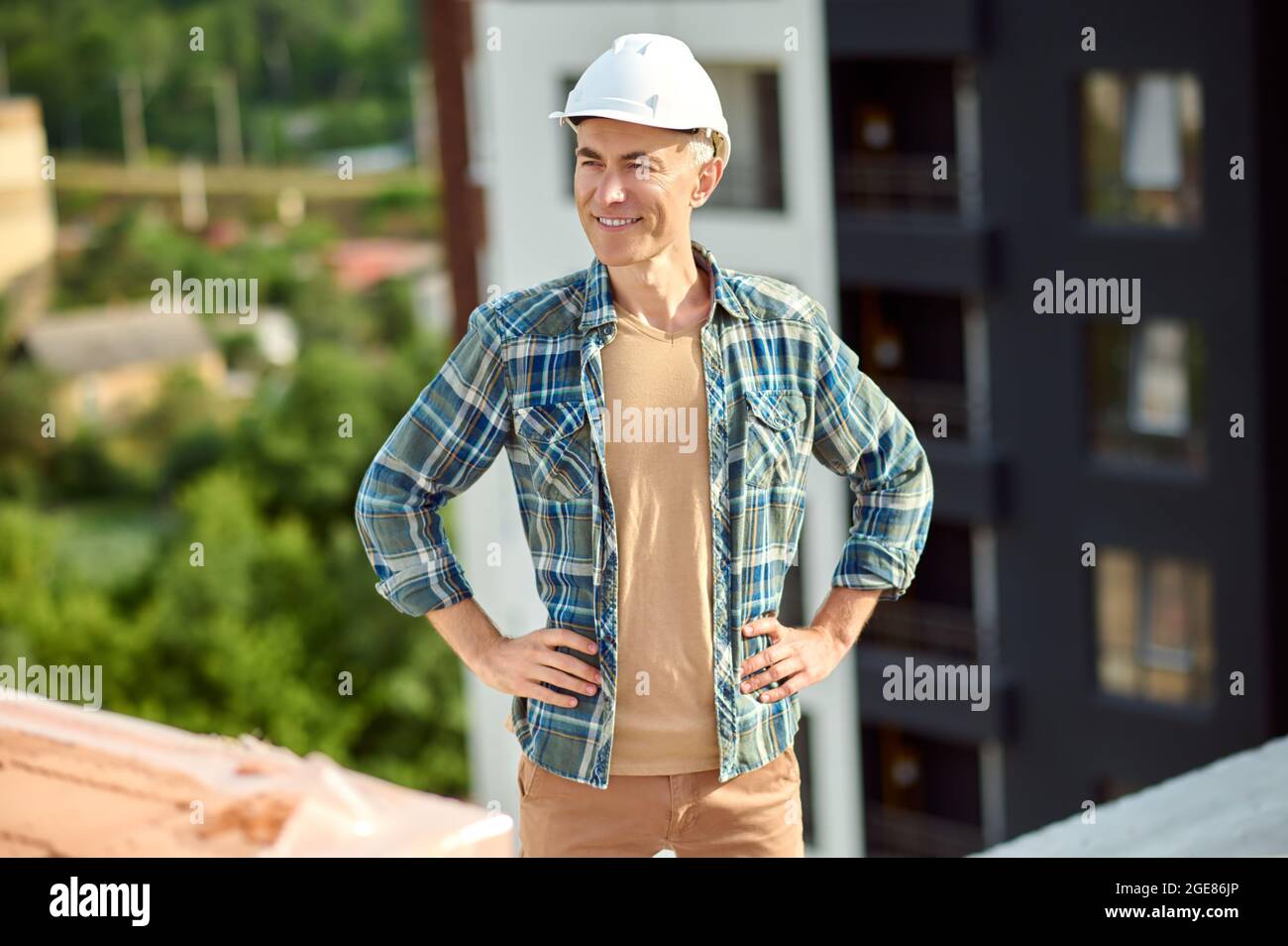 Un travailleur heureux au dernier étage d'une structure construite qui regarde loin Banque D'Images