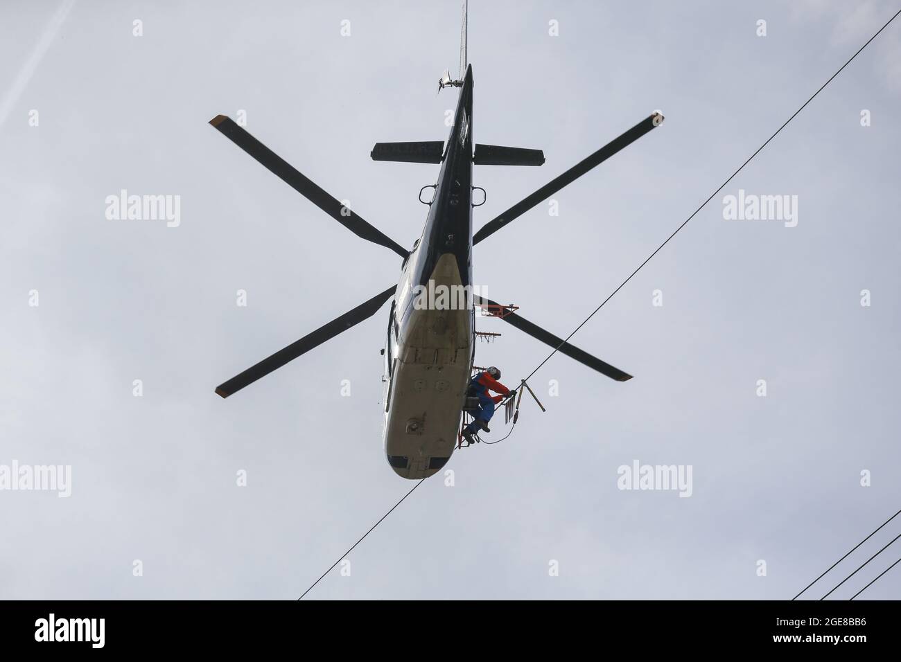 Placer des marqueurs de protection des oiseaux sur une ligne électrique avec l'aide d'un hélicoptère et d'un monteur assis à l'extérieur de l'Allemagne, Affoldern, 2017-04-10. Banque D'Images