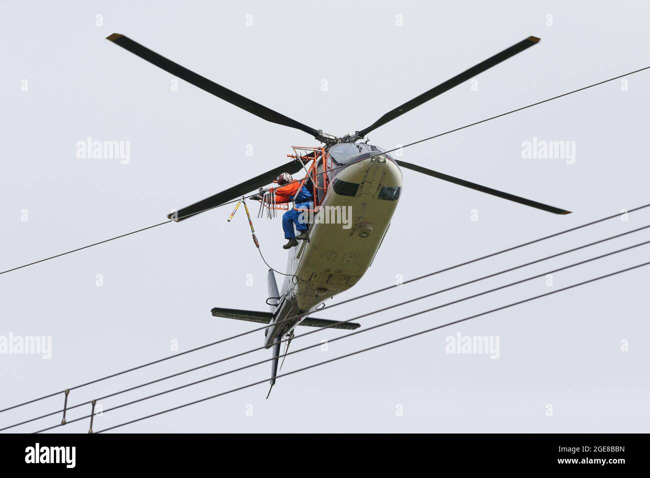 Placer des marqueurs de protection des oiseaux sur une ligne électrique avec l'aide d'un hélicoptère et d'un monteur assis à l'extérieur de l'Allemagne, Affoldern, 2017-04-10. Banque D'Images