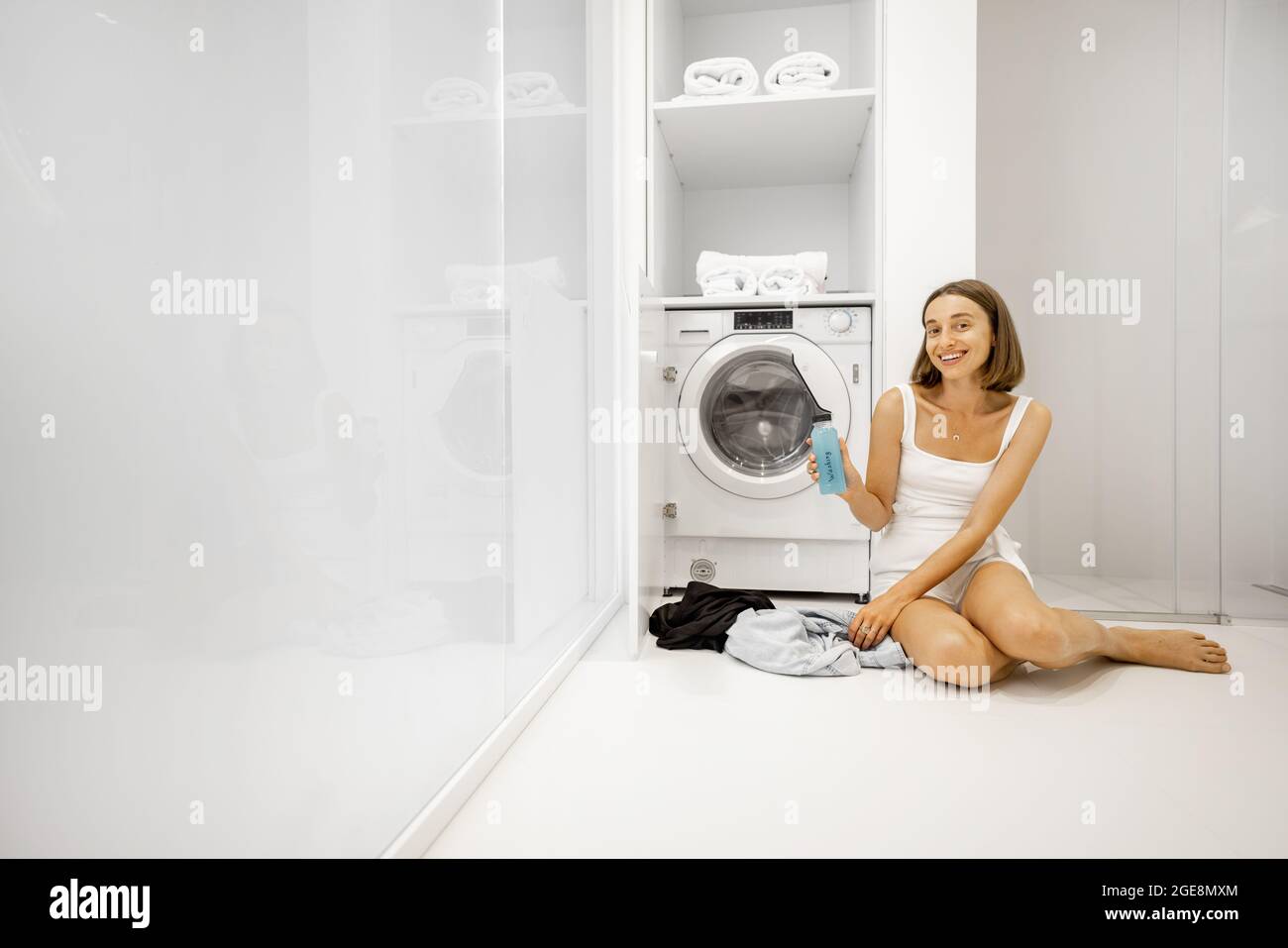Femme lavant des vêtements avec machine à laver dans la salle de bains Banque D'Images