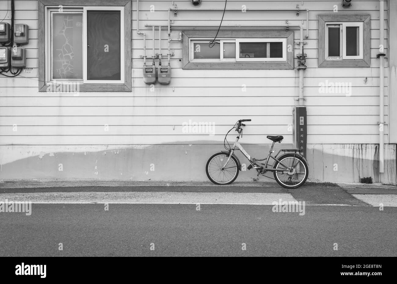 Photo en niveaux de gris d'un vélo devant une ancienne maison en bois capturée en Corée du Sud Banque D'Images