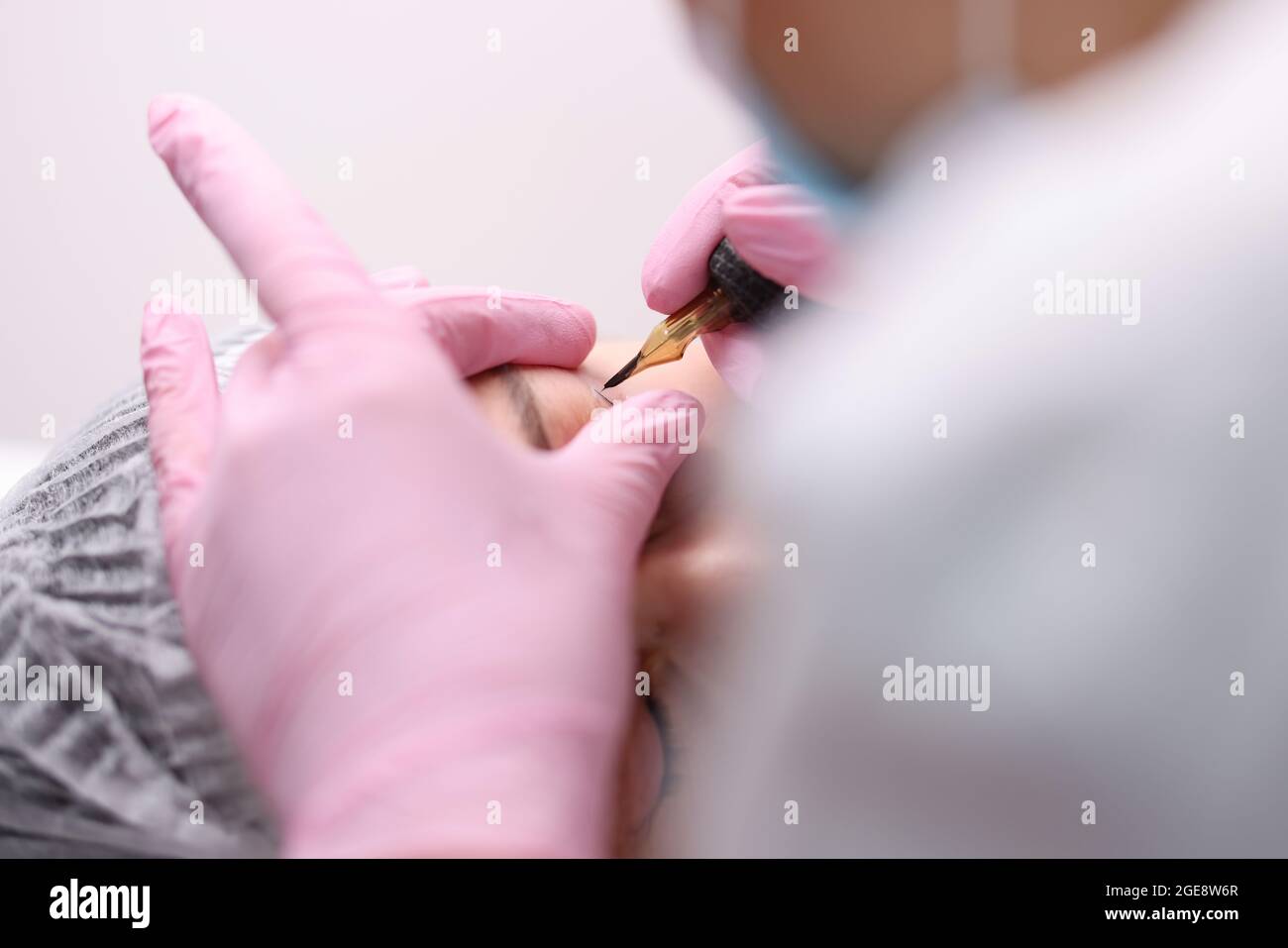 L'artiste de maquillage permanent fait des flèches pour les yeux pour le client de gros plan Banque D'Images