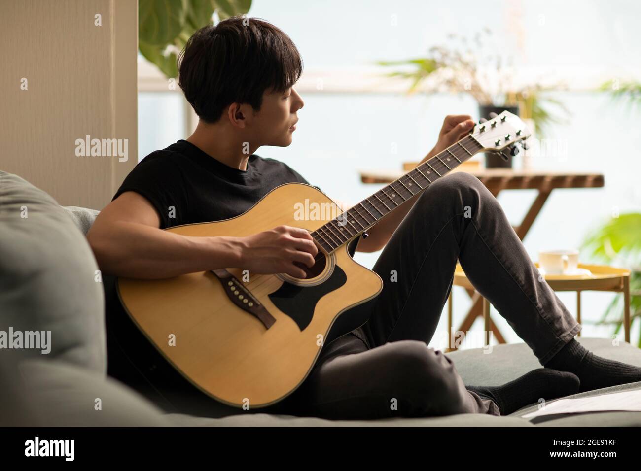 Jeune homme chinois jouant de la guitare à la maison Photo Stock - Alamy