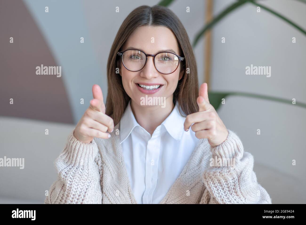 Femme à cheveux longs en lunettes souriant joliment et regardant content Banque D'Images