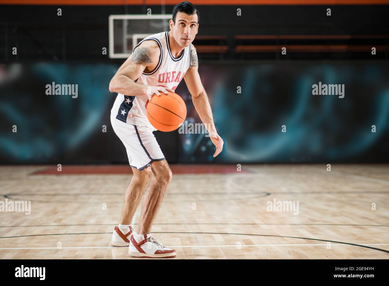 Jeune homme sportif en vêtements de sport blancs jouant basket-ball dans la  salle de gym Photo Stock - Alamy