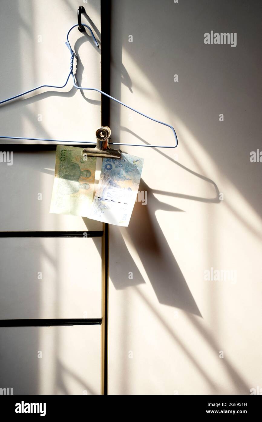 Les billets de banque thaïlandais sont suspendus sur un cintre avec des trombones sur un meuble blanc brillant. Banque D'Images