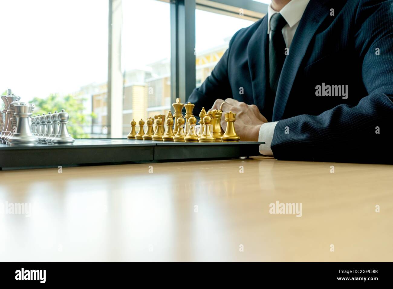 Un homme d'affaires portant un costume se prépare à jouer aux échecs devant le concept de stratégie d'échecs de conseil avec plus d'espace de copie Banque D'Images