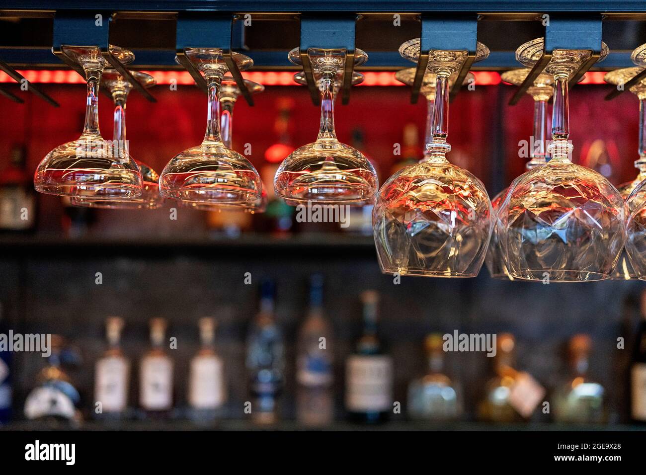 Plusieurs verres en cristal propres de forme et de taille différentes suspendus sur les étagères au-dessus du comptoir dans le bar Banque D'Images