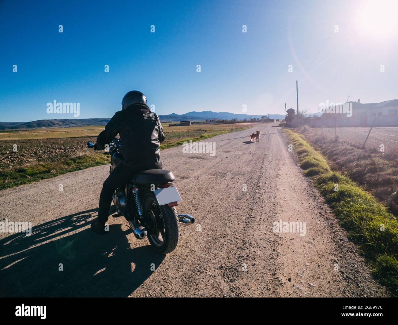 Personne avec vue arrière conduisant une moto sur la route rurale en plein soleil dans la campagne Banque D'Images